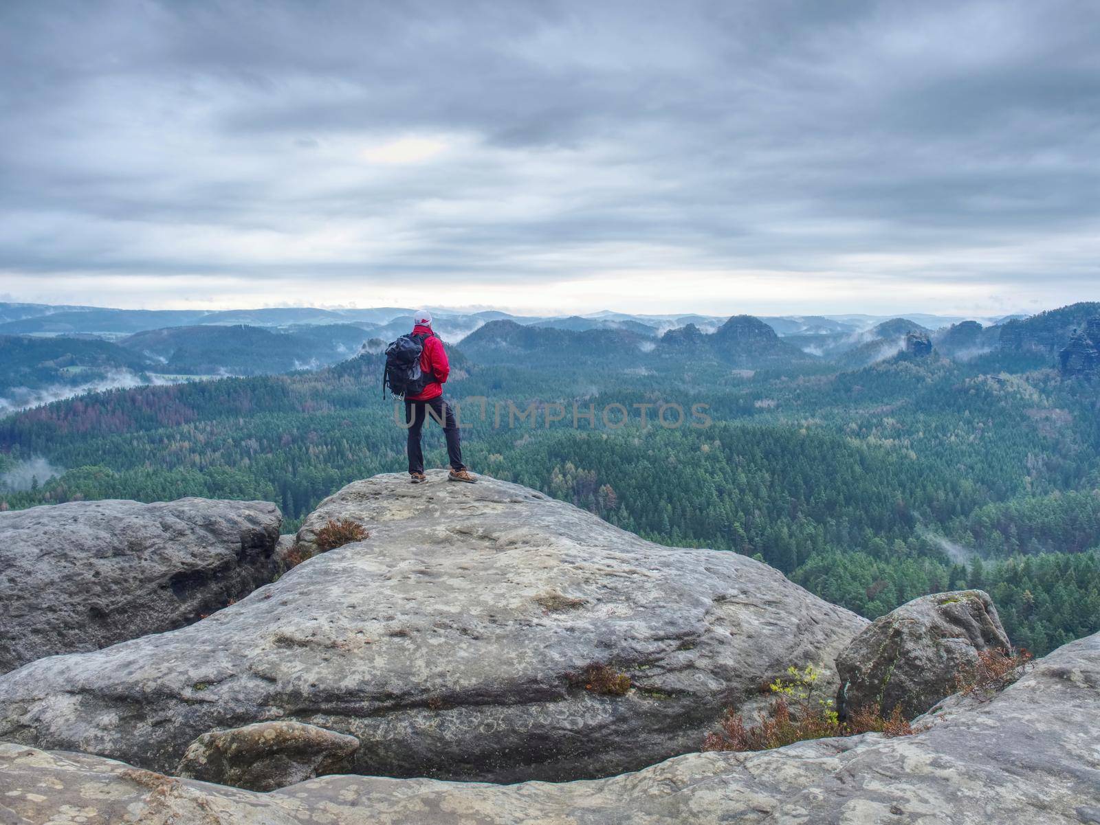 Outdoor photographer with tripod and camera on rock thinking by rdonar2