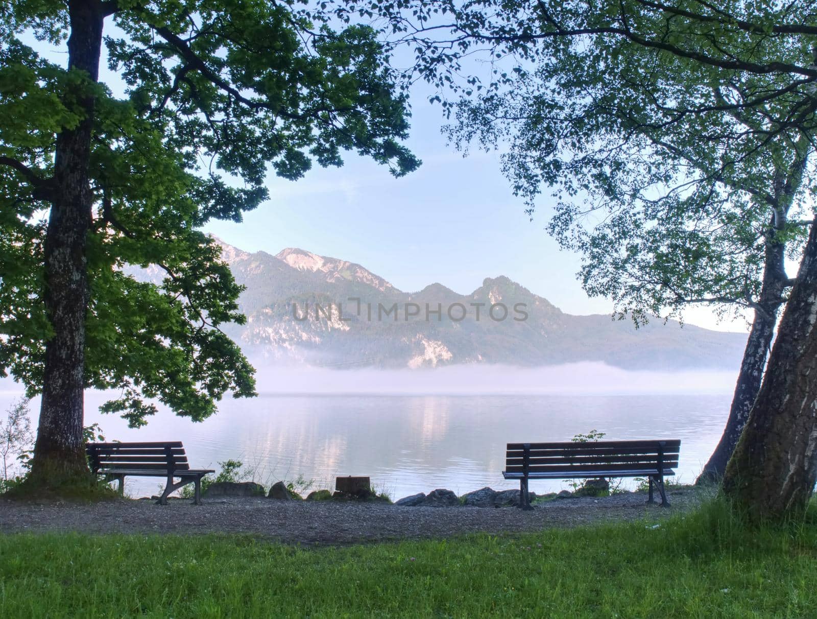 Empty bench at the lake beach. Magnificent lake in South Bavaria, Germany.  by rdonar2