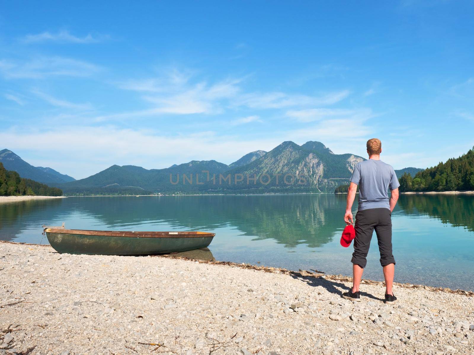 Modern sport fishing paddle boat anchored on shore of the lake bay. Peaceful level of lake. Windless sunny day.