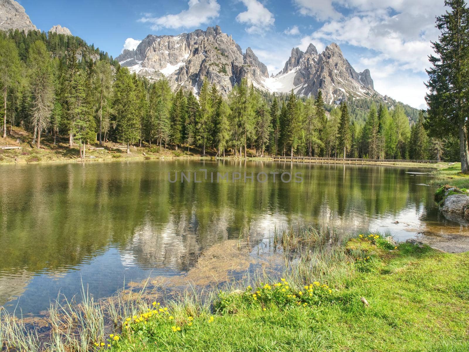 The calm blue lake between the sharp rocks. Mountain peaks touching to dramatic sky with clouds. Wonderful valley. Hiking and Tourism Concept