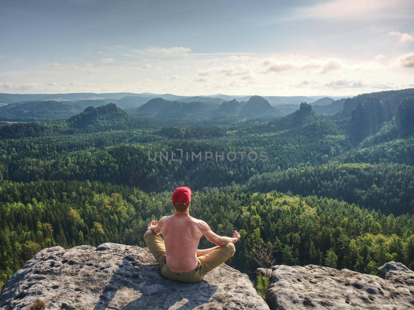 Shirtless man in yoga pose. Sportsman doing an Outdoor Yoga Exercise Sitting against 