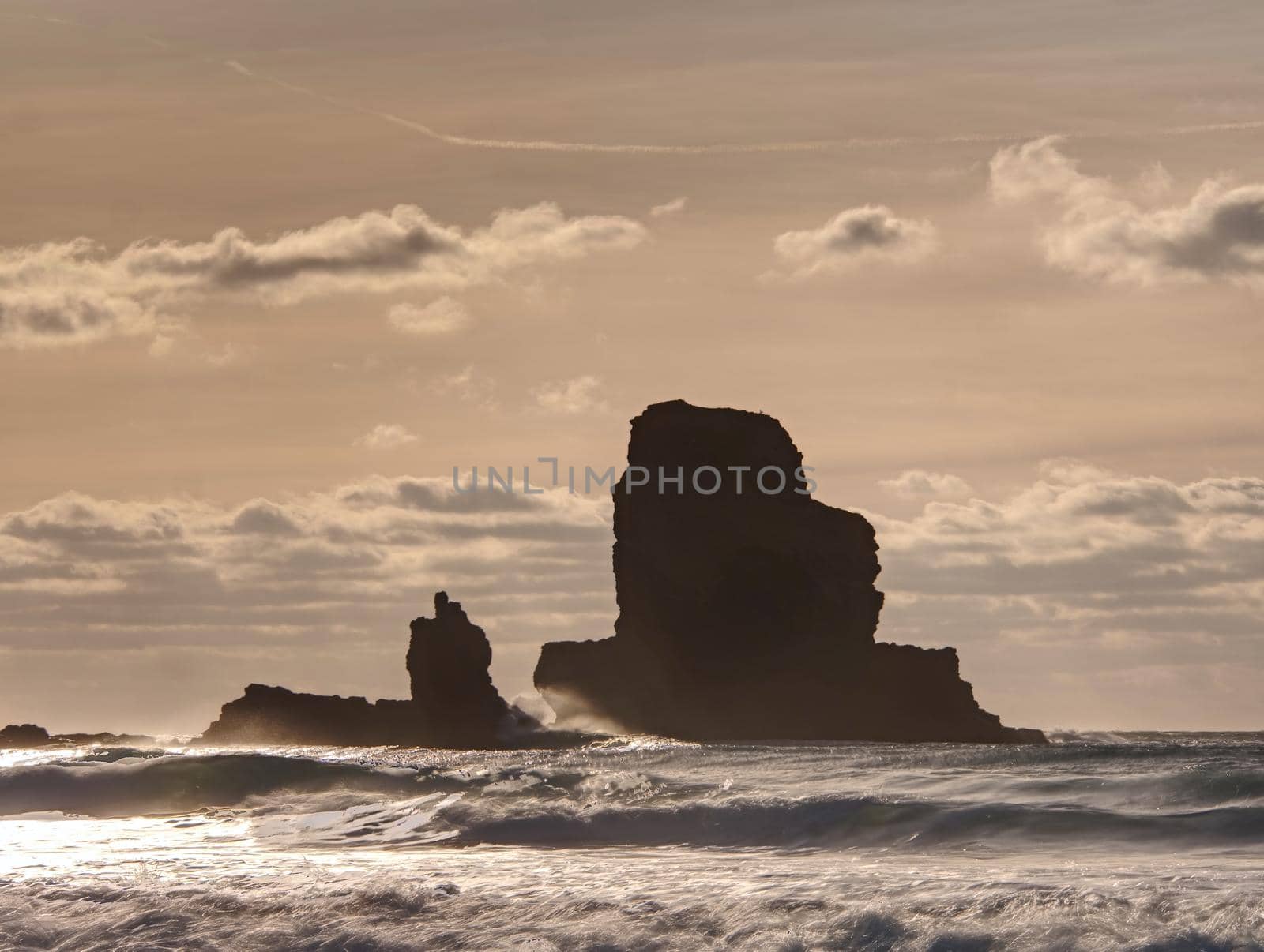 Evening Bay. Sharp rocks, black rounded boulders, stony beach, sand and dark sky.