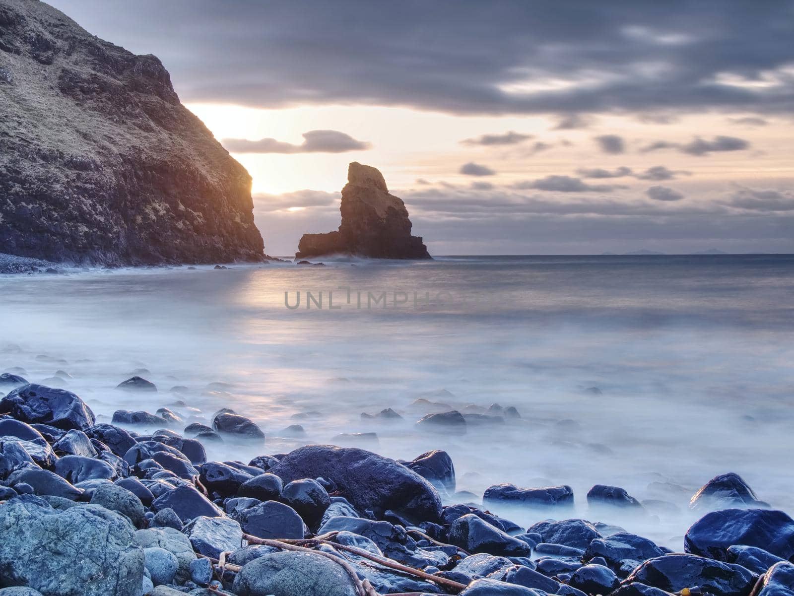 Blue sunset at rocky coast of sea. Slow shutter speed for smooth water level and dreamy effect