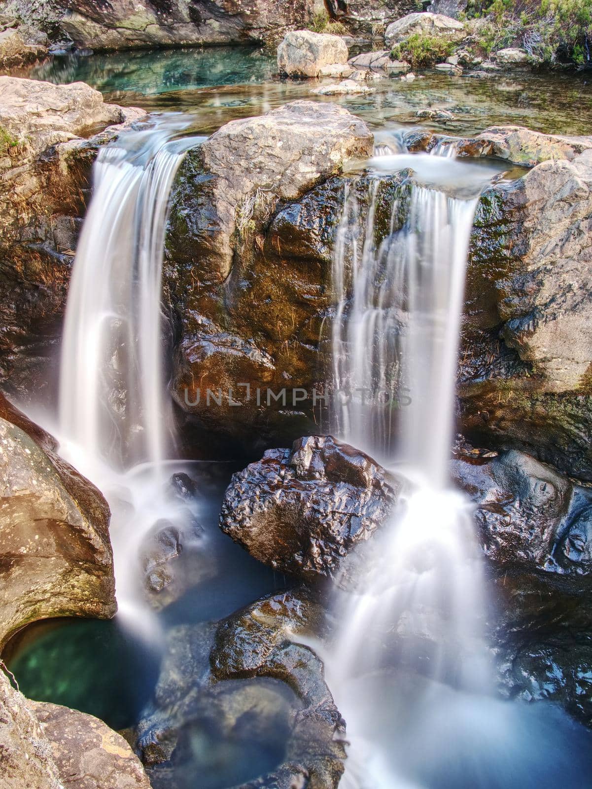 Blue water of river Brittle in trail known as Fairy pools. The mountain river cut in soft rocks colorful pools.  Bellow the mountains of Glenbrittle on Isle of Skye Scotland