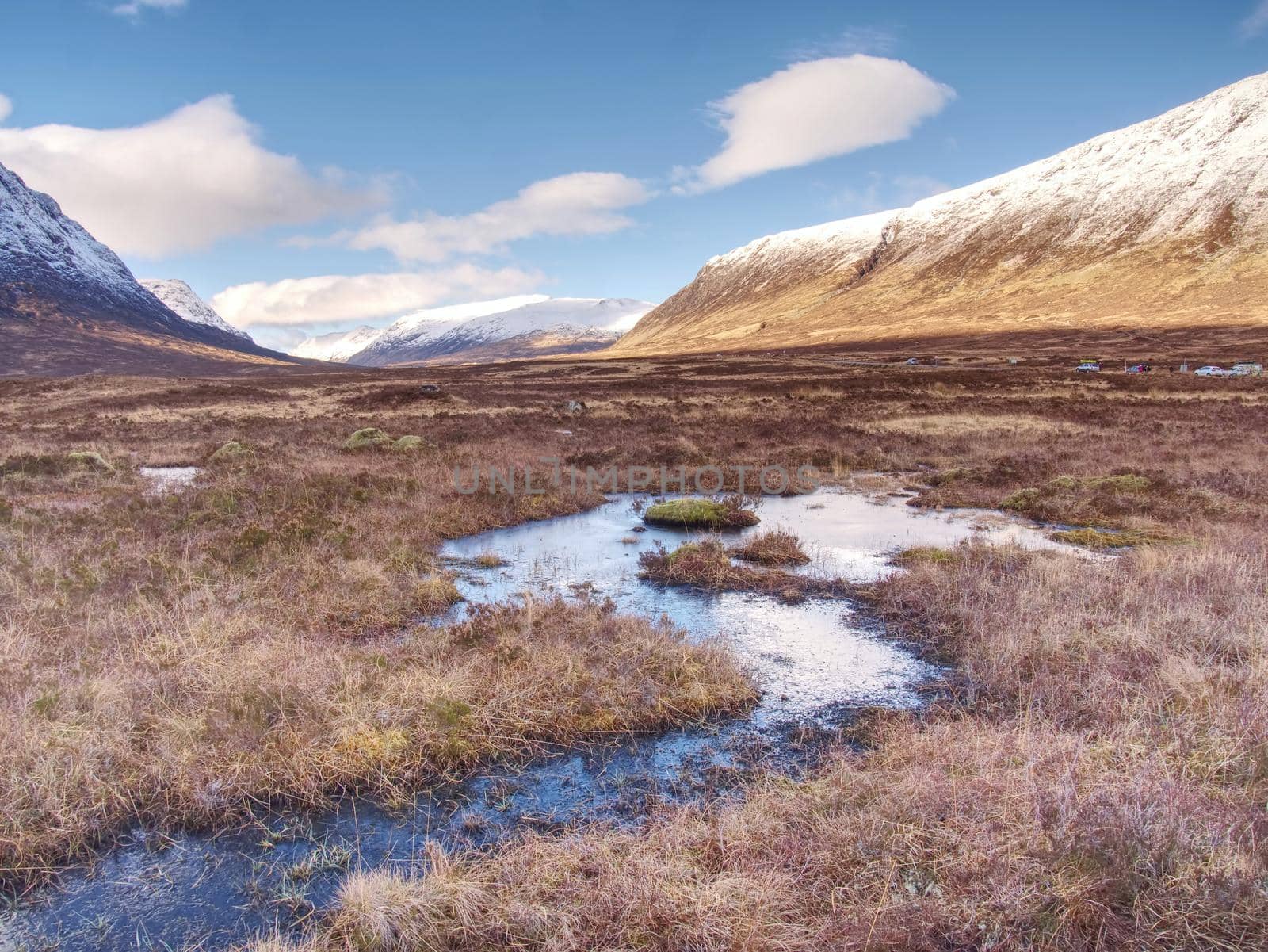 River at base of snowy mountains in Scottish Highlands near Glencoe  in winter. Cold windless winter morning