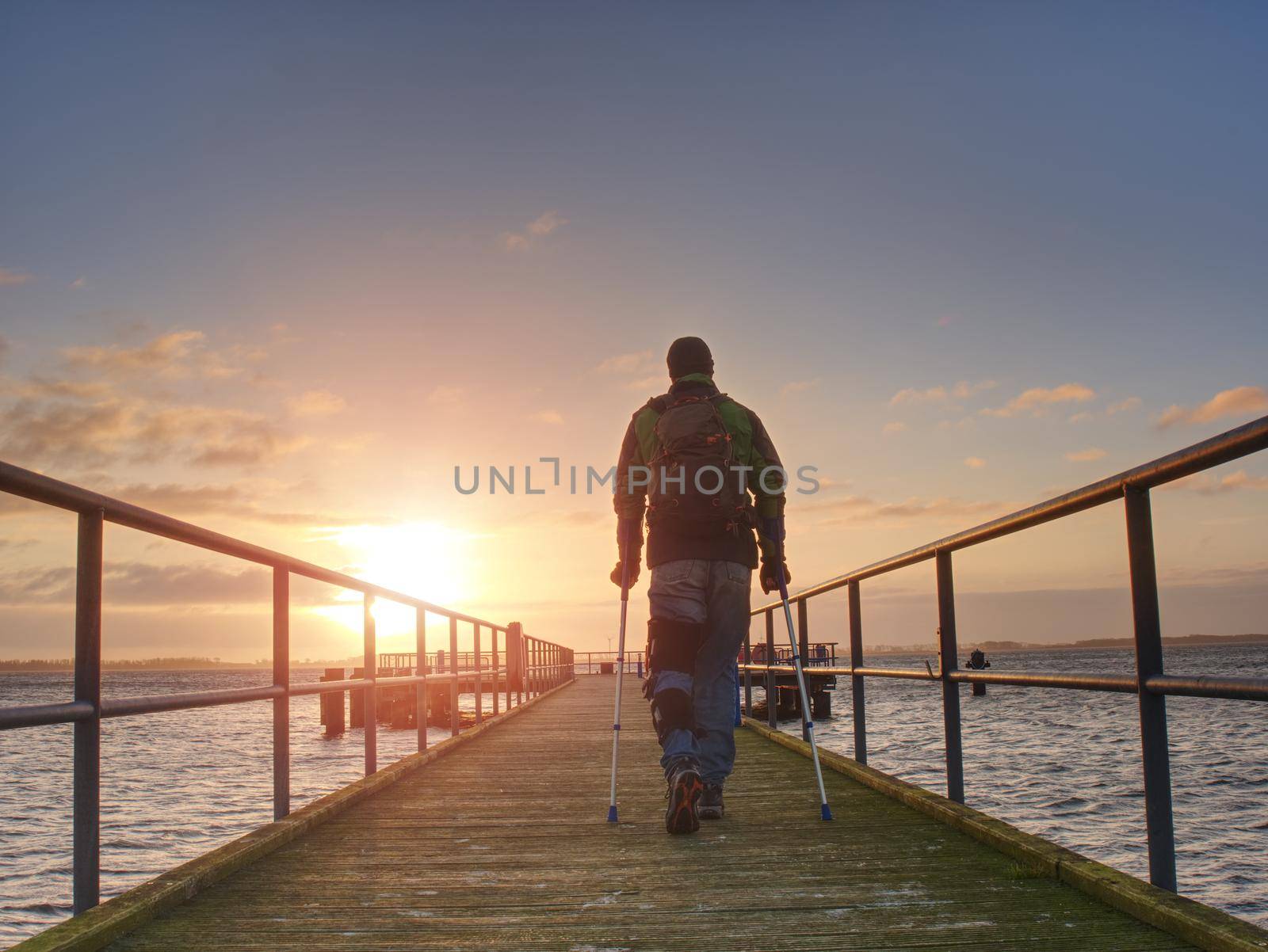 man silhouettes on a bridge against the setting sun, clear colorful sky