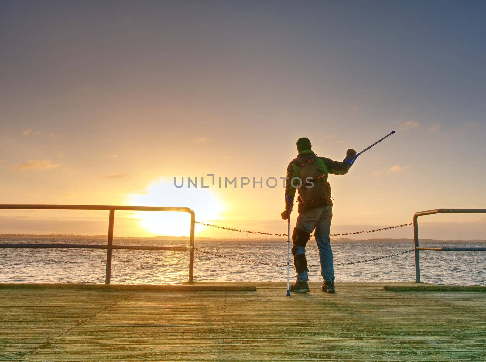 Man hiker stand alone and watching sunrise above sea bridge by rdonar2