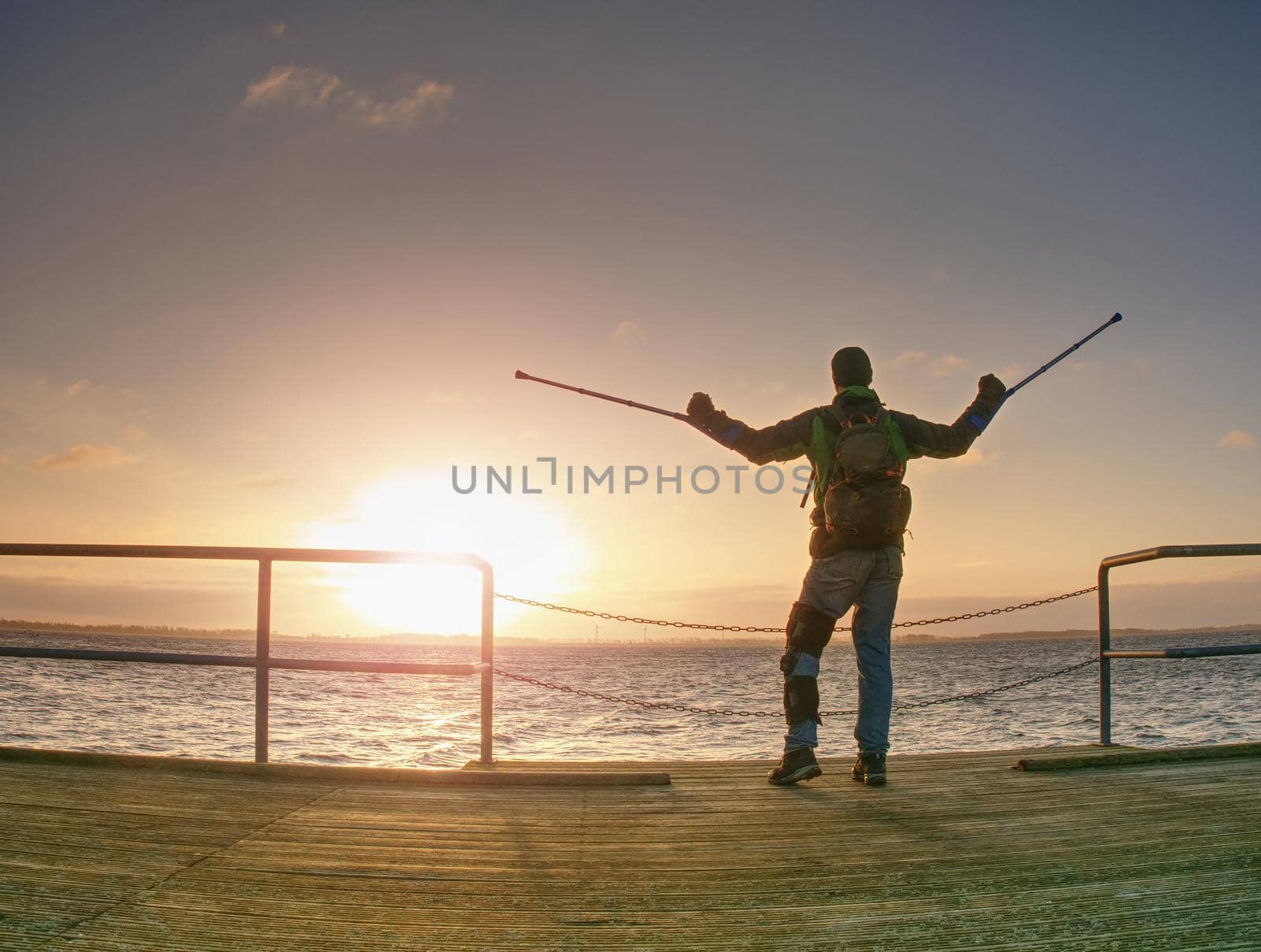 Morning passanger on ferry pier in dock wait for firts ferry boat. Sunrise above horizon.