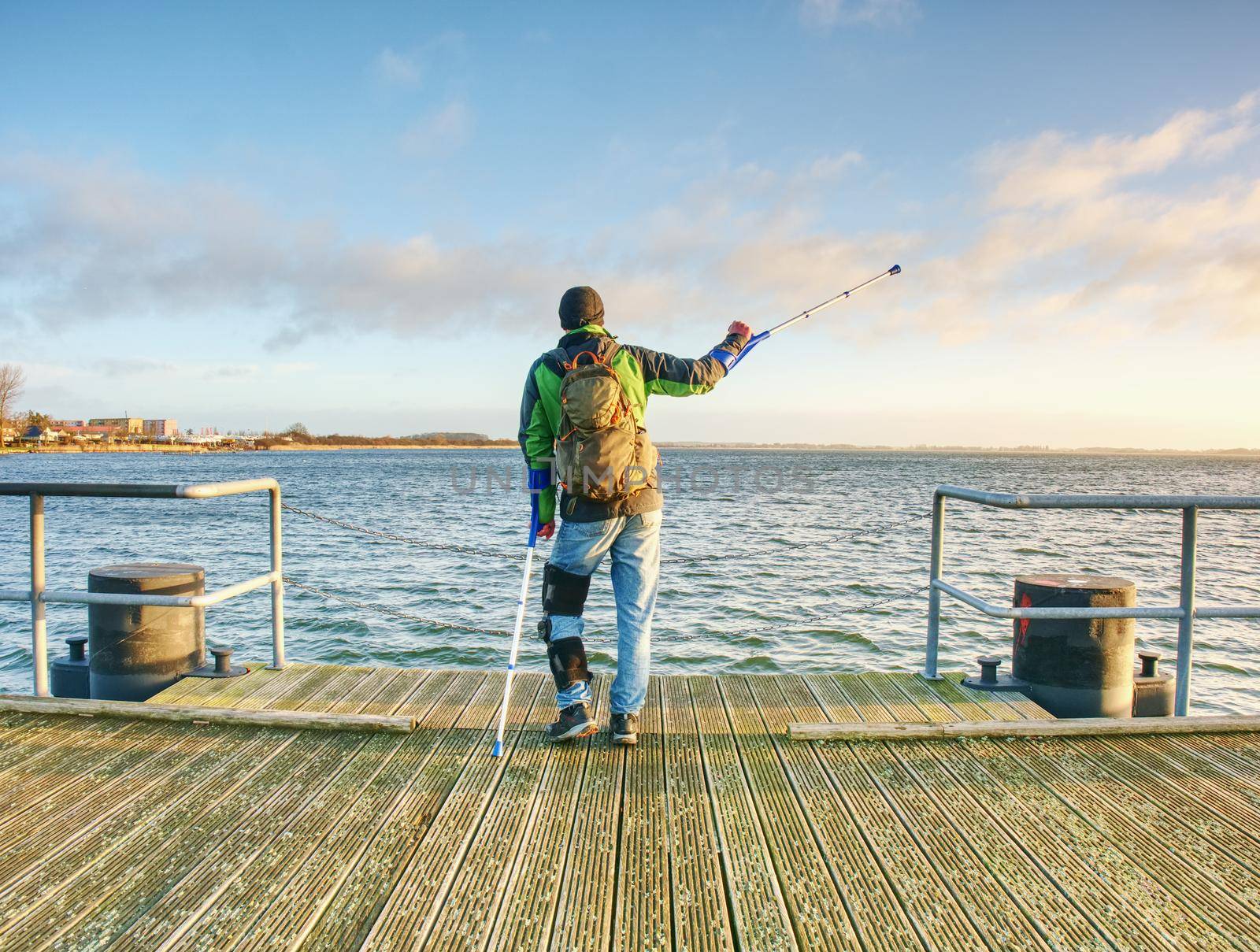 Man with a crutches on mole pier. Tourist with broken leg on crutches by rdonar2