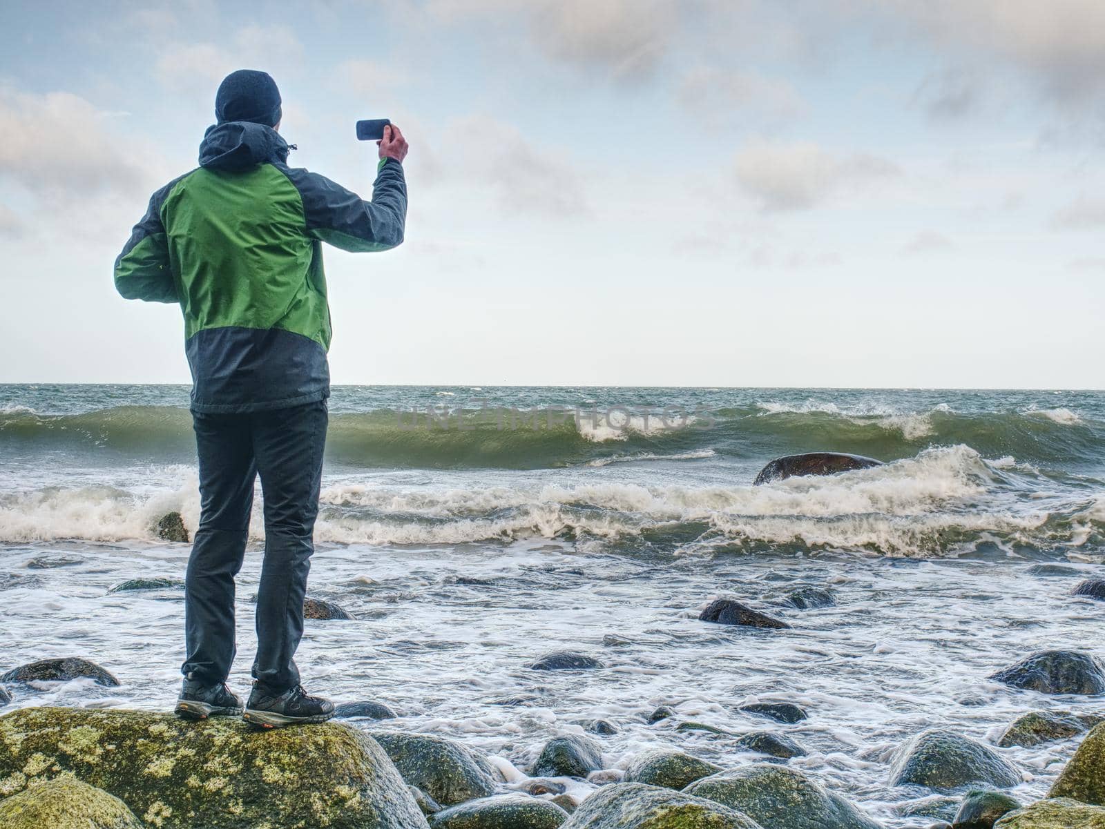 Tourist figure stand on rocky stony coast. Sun beams by rdonar2