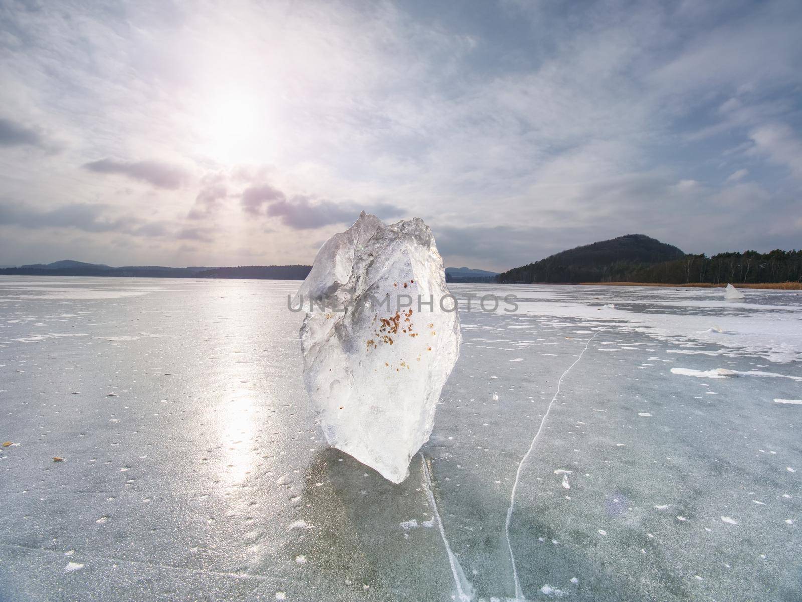 Ice breaking. Floe on frozen lake with sunset sky background,