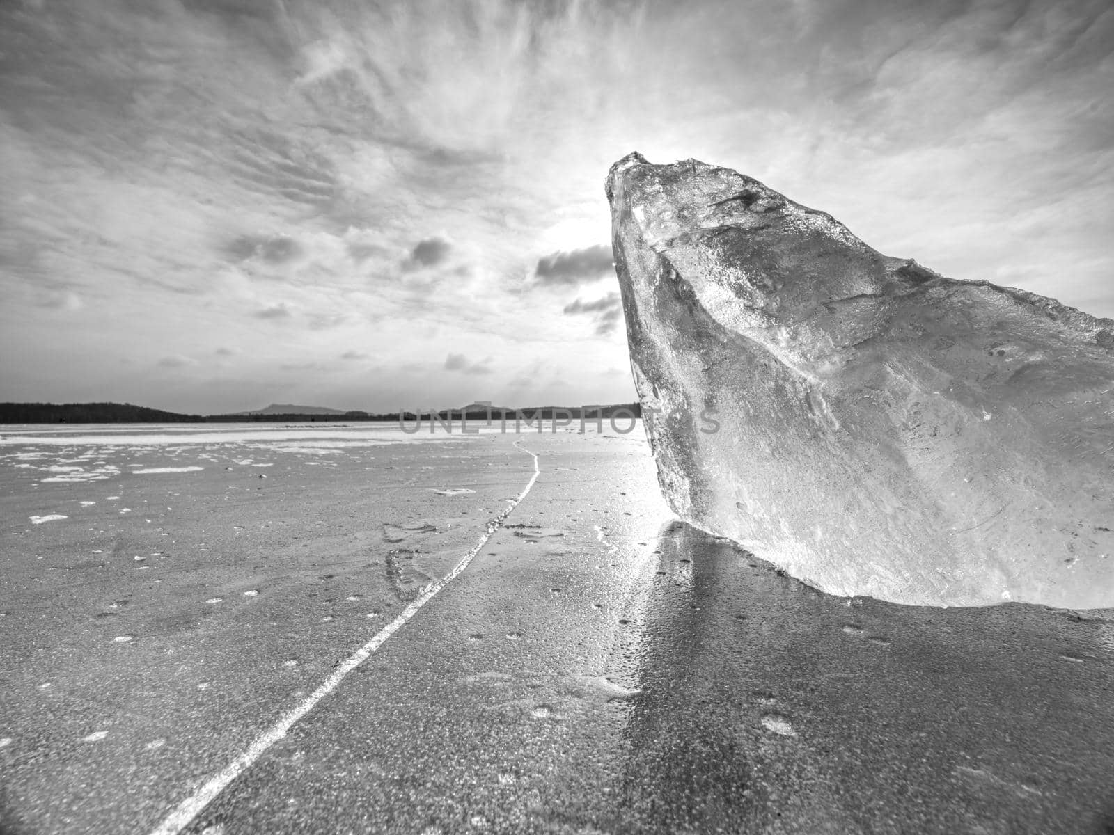 Arctic cold landscape of icy lake at sunset with cracks and patterns on the ice. Winter landscape 