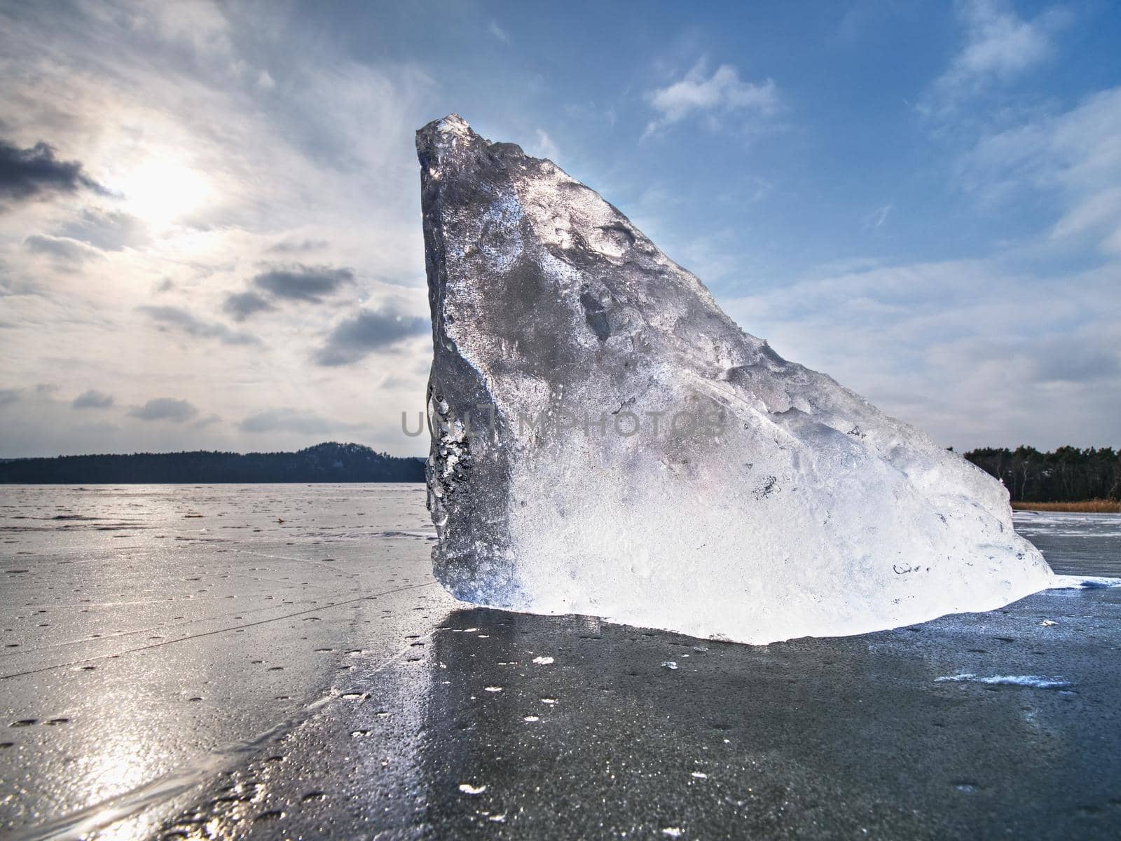 Ice breaking in pure nature. View over frozen water lake with sunset sky background,  winter natura landscape