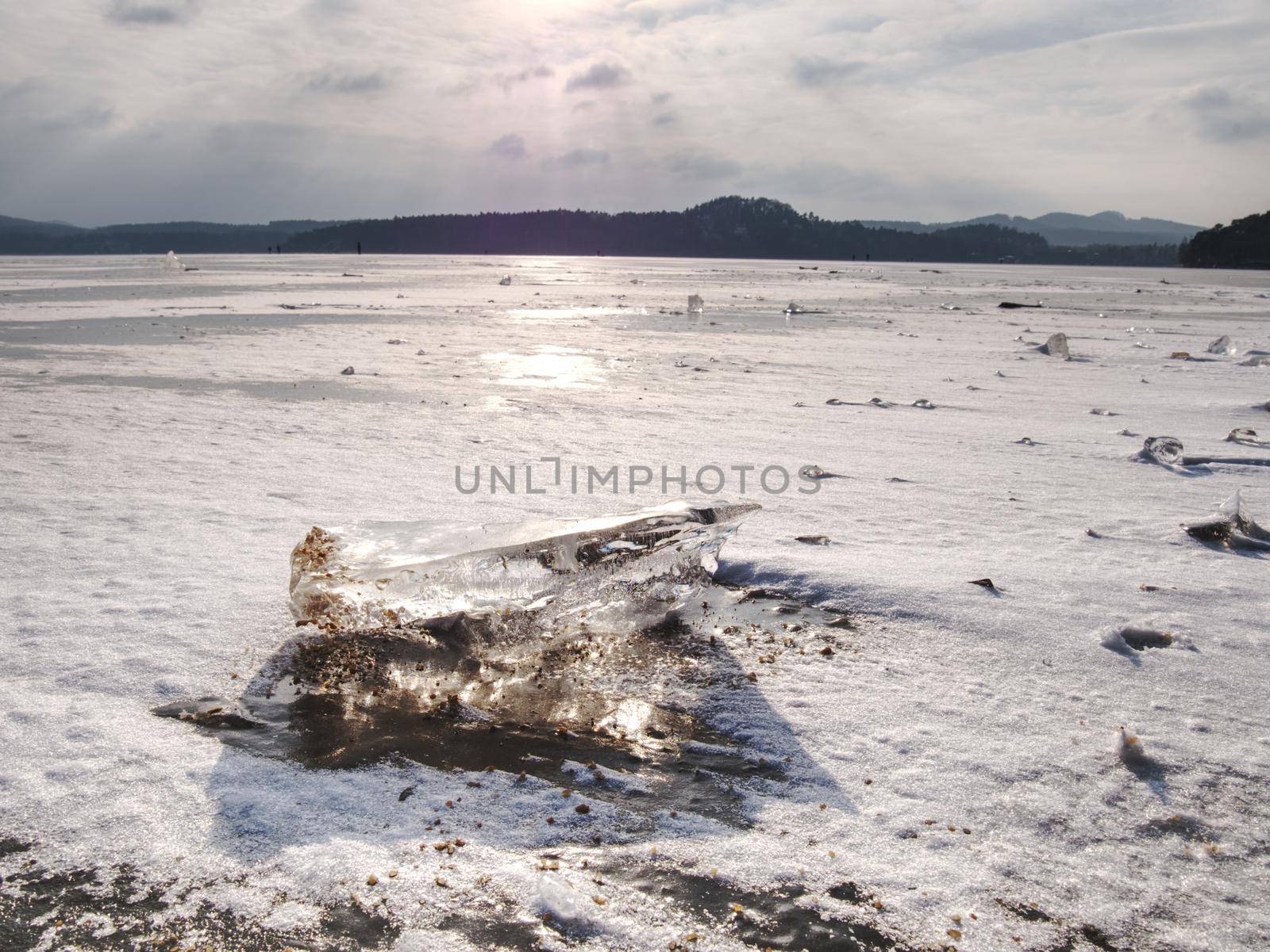 Ice breaking. Floe on frozen lake with sunset sky background,