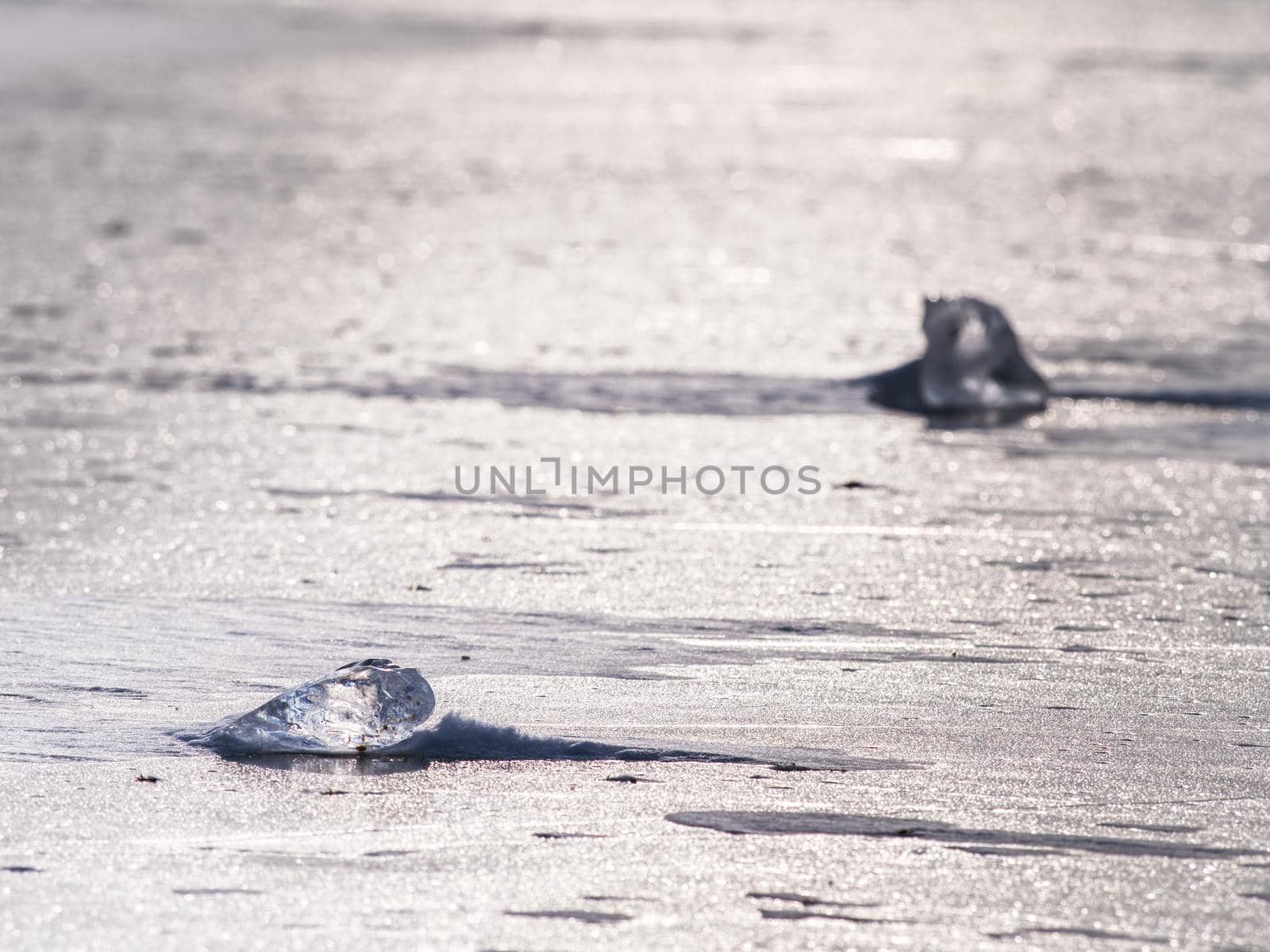 Sun shining through the transparent  ice floe. Water under transparent ice cover in silent bay. 