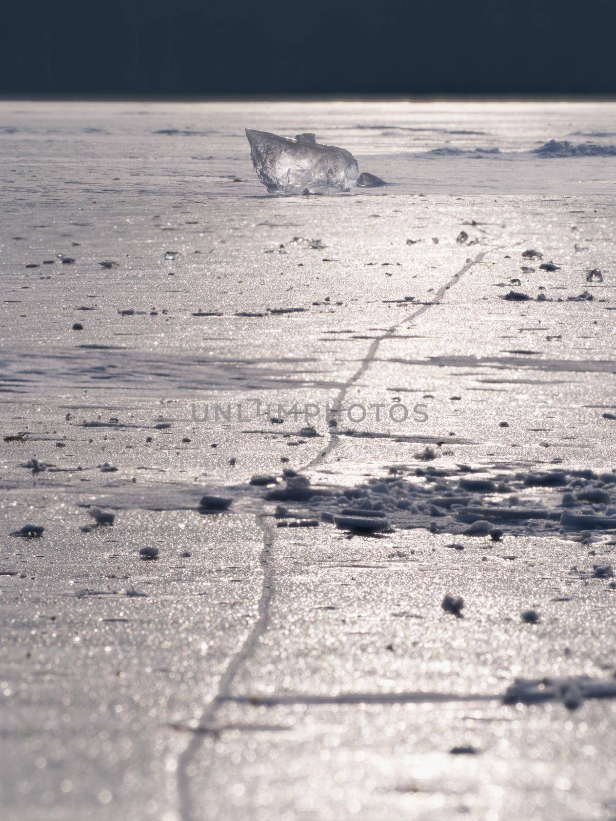 Abstract ice floe on frozen lake. Weathered ice and sparkling of sun rays.  by rdonar2