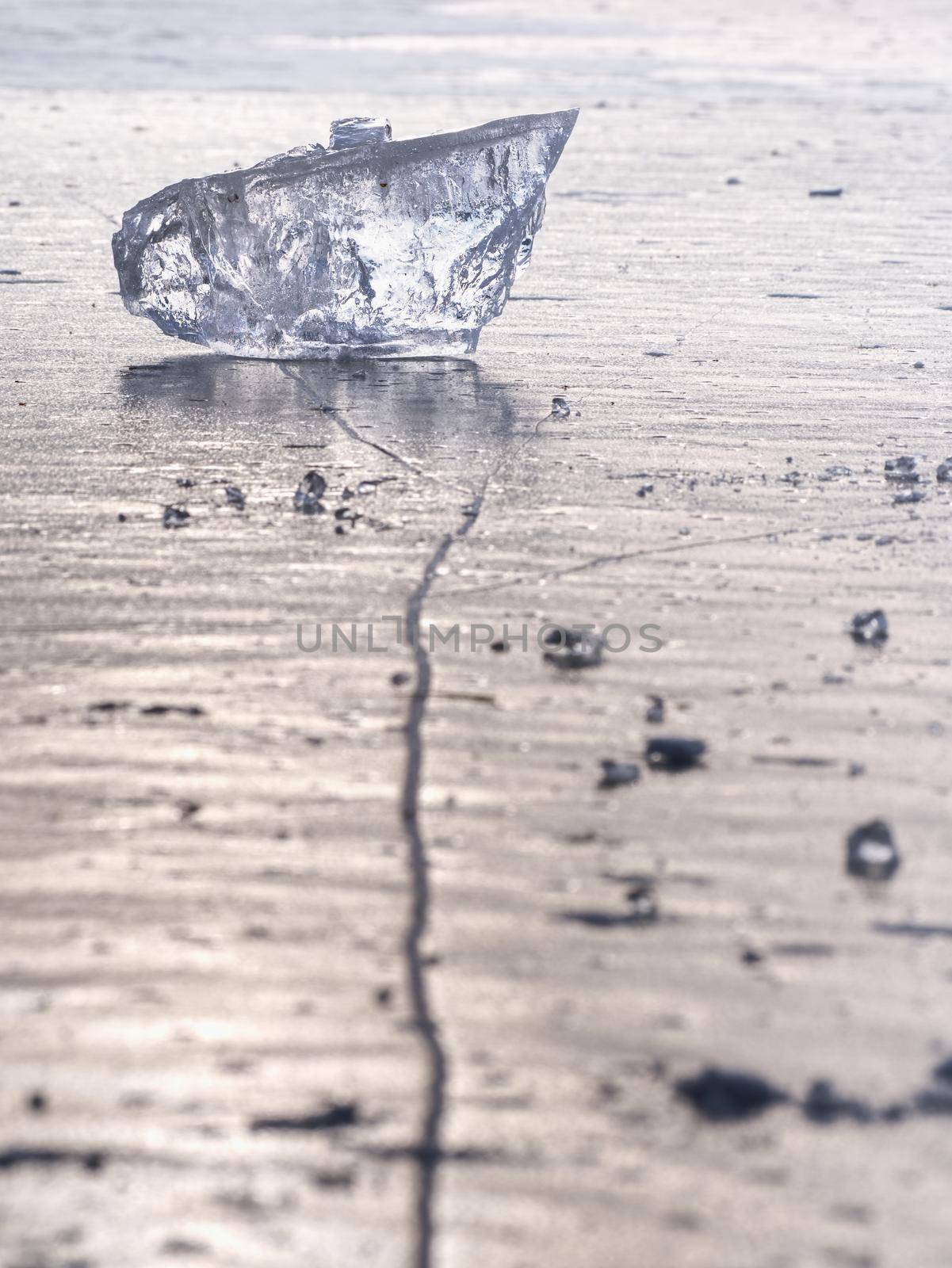 sparkling shards of cracked ice jut out on the frozen lake. The light effect occurs in deep and shallow cracks of sublime ice. Follow the depth of field