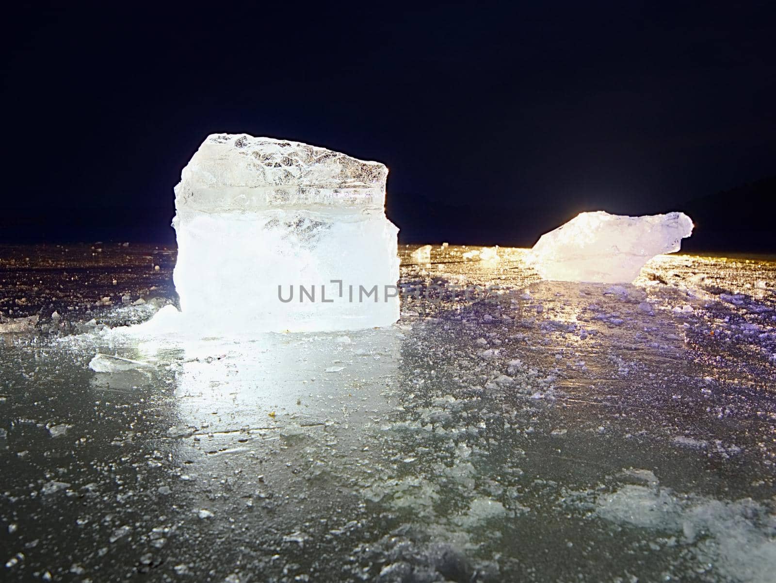 ice piece in blue shadows, on dark natural background. Ice in backlight