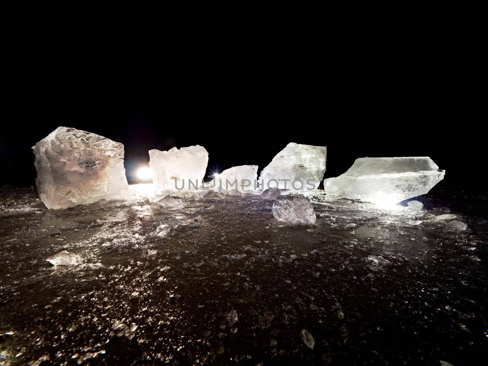 Cut ice. Crushed cubes lighted with strong backlight.  Silent bay  with flat frozen level.  The light spectre in ice.