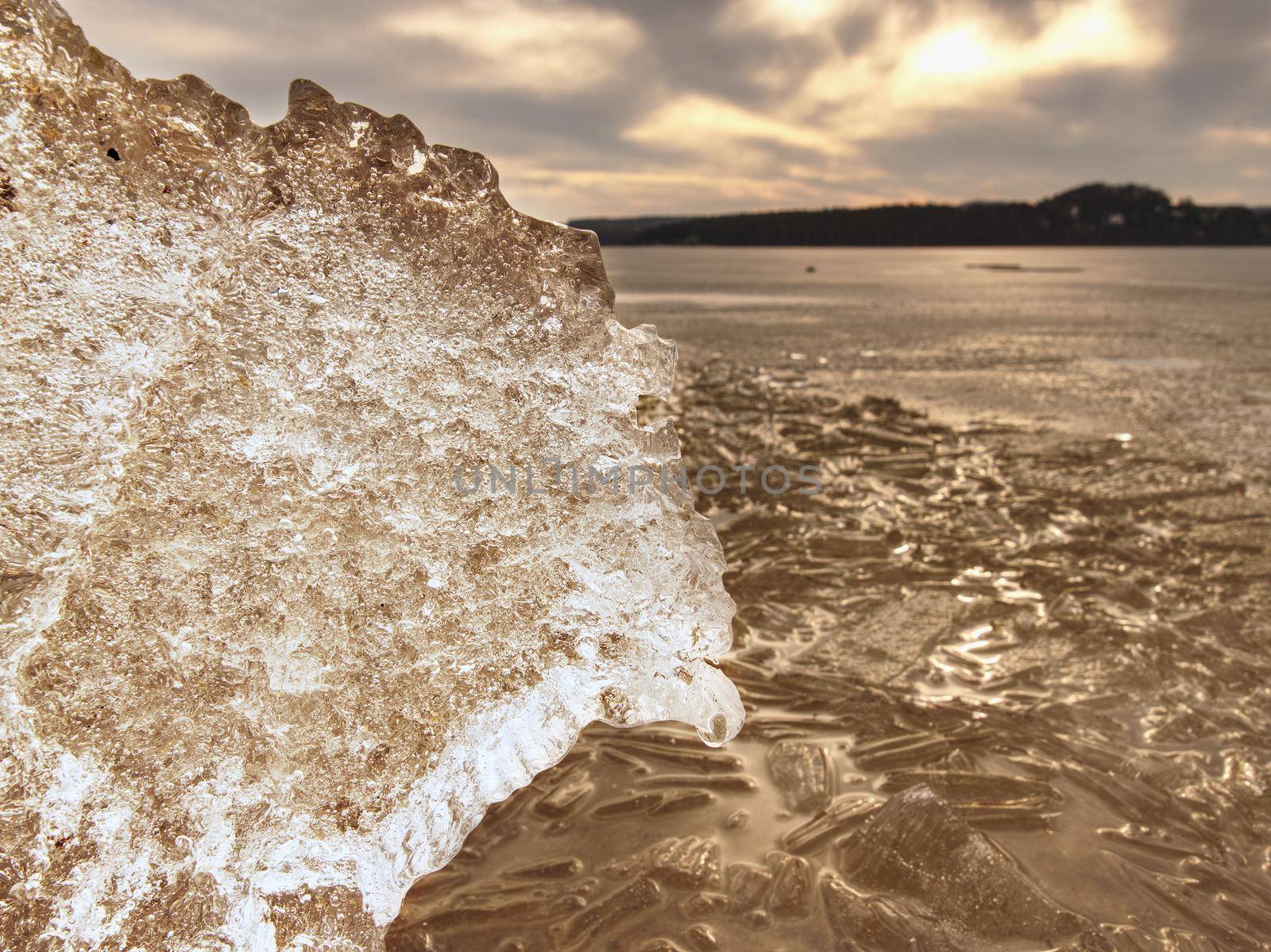 Structured frozen mud. Shore of frozen puddle against to the sunlight.