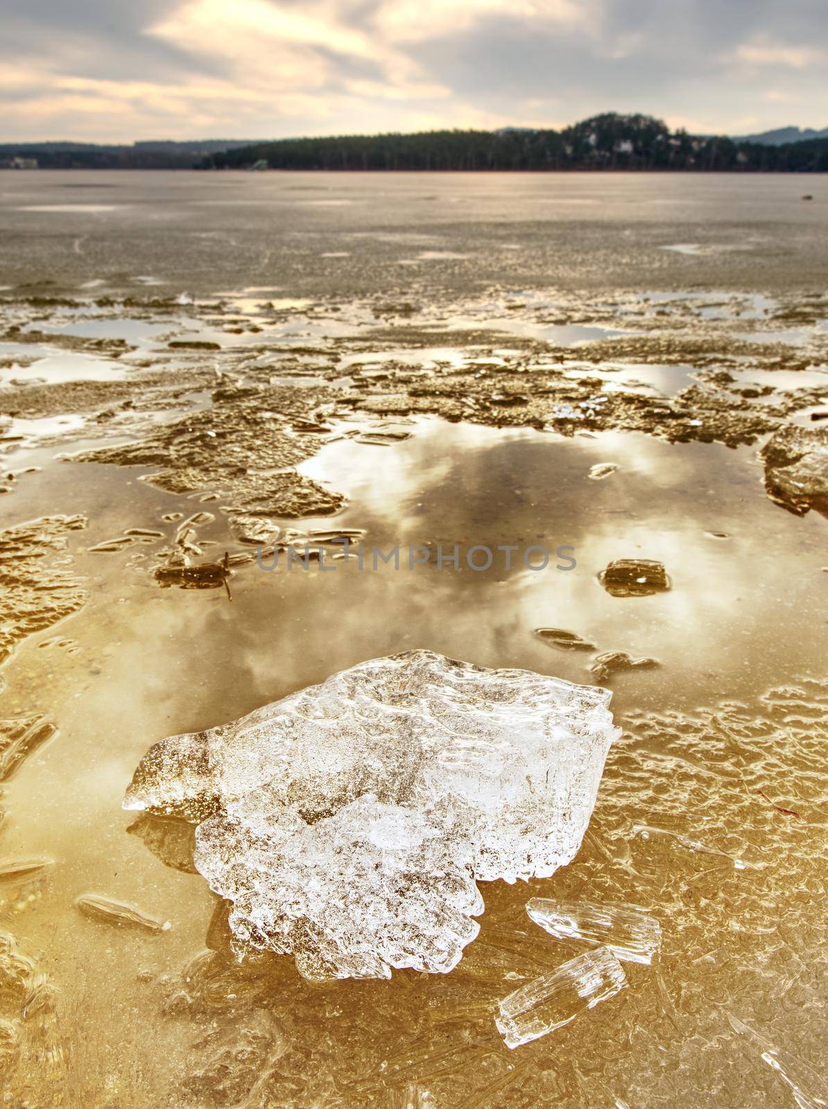 Winter natural wonder. Yellow pieces of snow melting on beach. Wonderful nature creation.