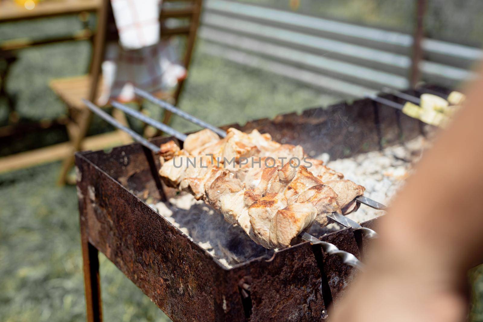 Close up of kebabs on skewers, man grilling meat outdoors by Desperada
