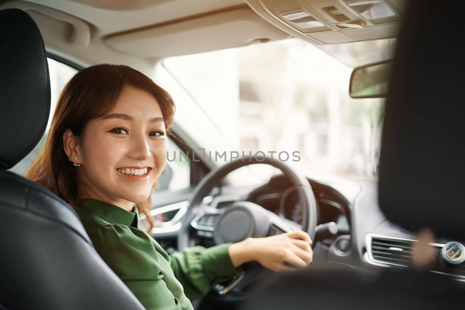 Confident and beautiful. Rear view of attractive young woman in casual wear looking over her shoulder while driving a car