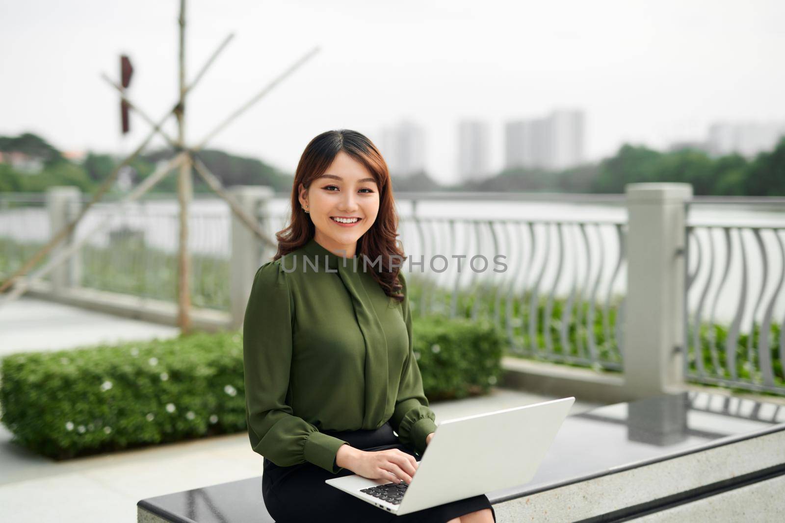 Young business woman using laptop sitting in the park.