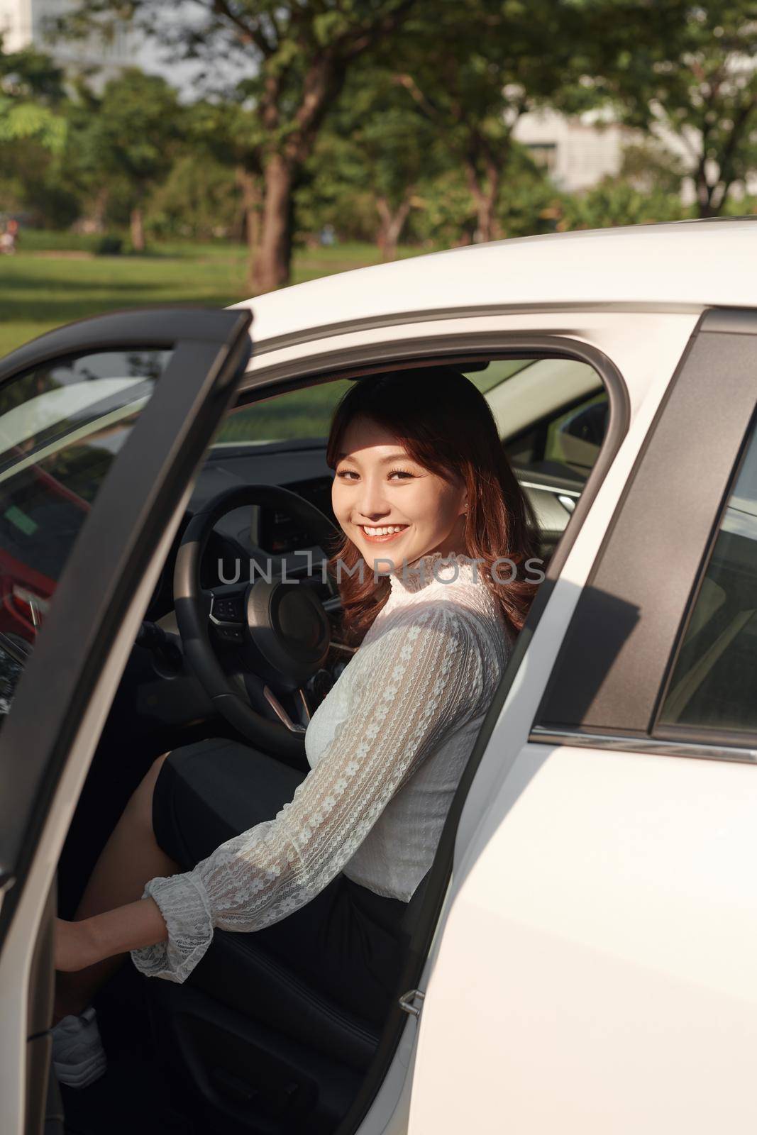 Photo of happy young mixed race woman sitting inside her new car. Concept for car rental by makidotvn