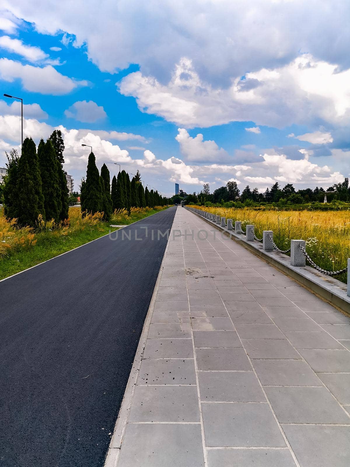 Long pavement and bike path next to road and Soviet Officers Cemetery  by Wierzchu