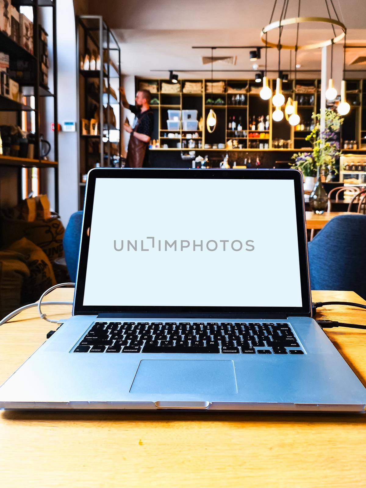 Working with laptop at wooden table in small cafe by Wierzchu