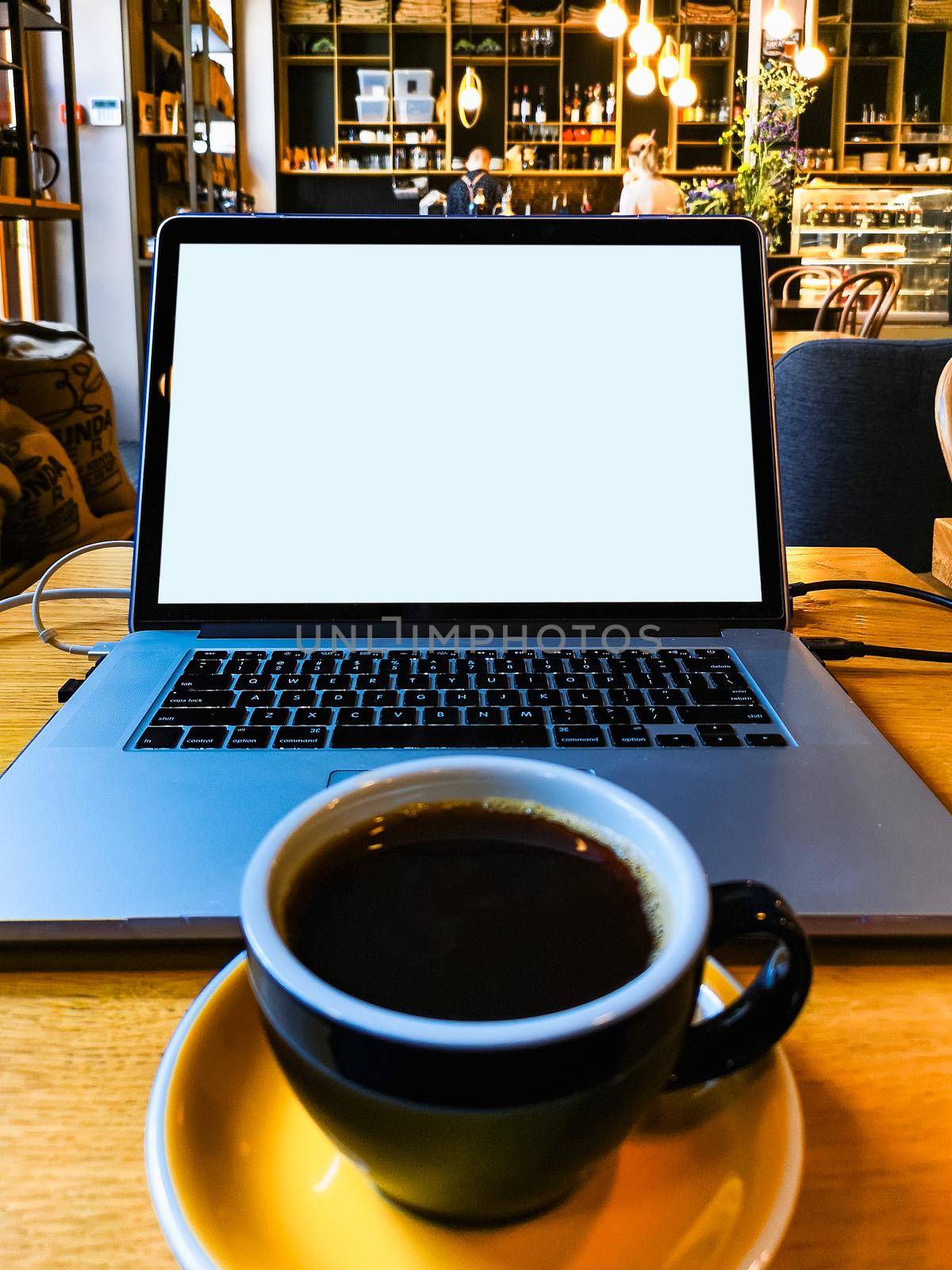 Working with laptop and coffee at wooden table in small cafe