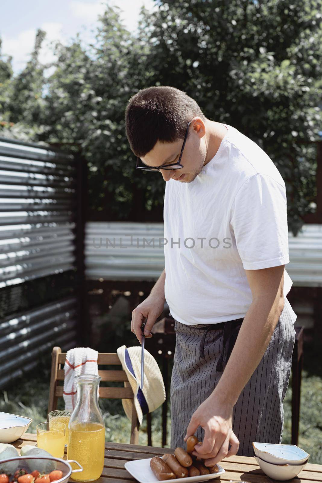 Backyard barbecue. Mans hands grilling kebab and vegetables on metal skewers.