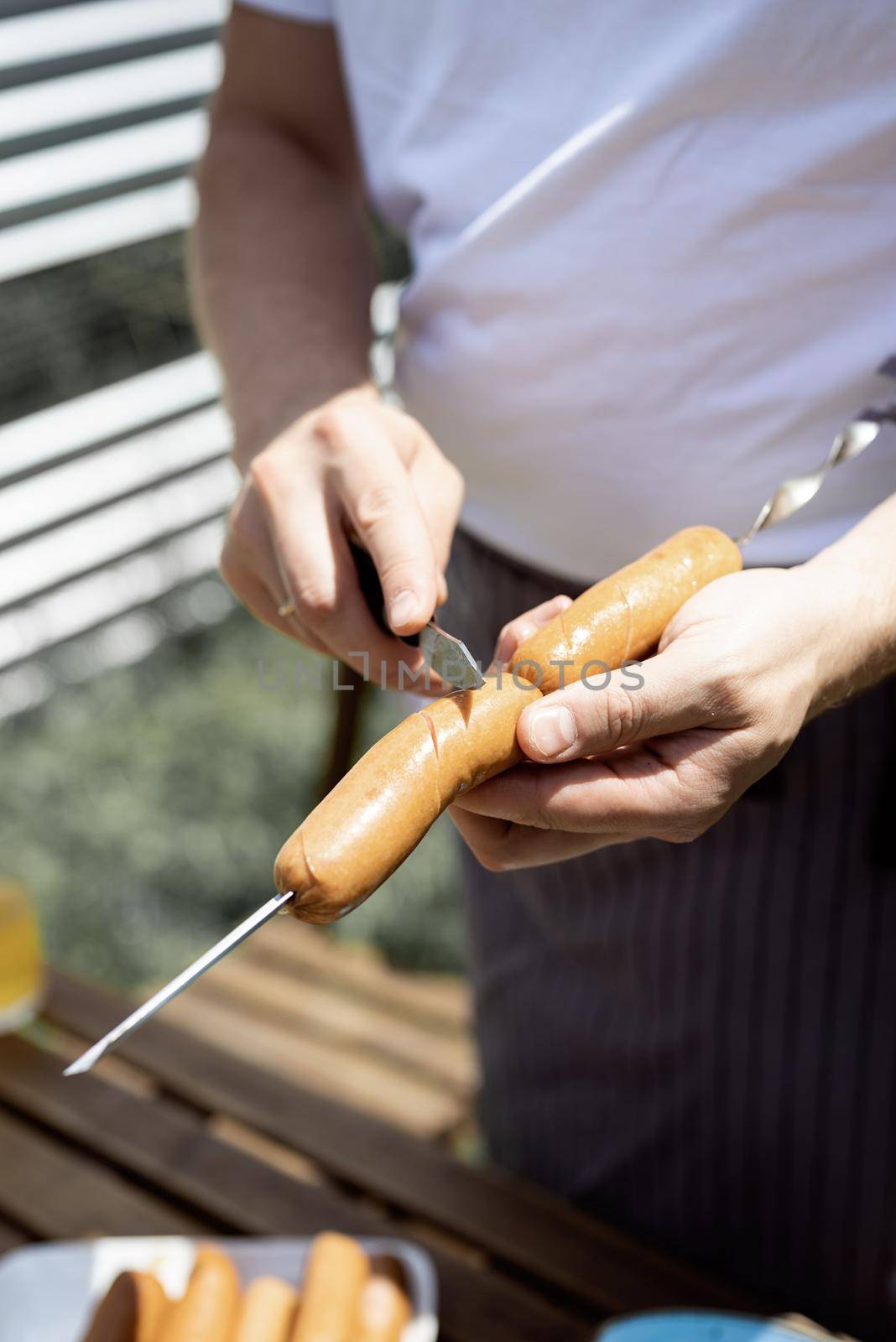 Young man grilling kebabs on skewers, man grilling meat outdoors by Desperada