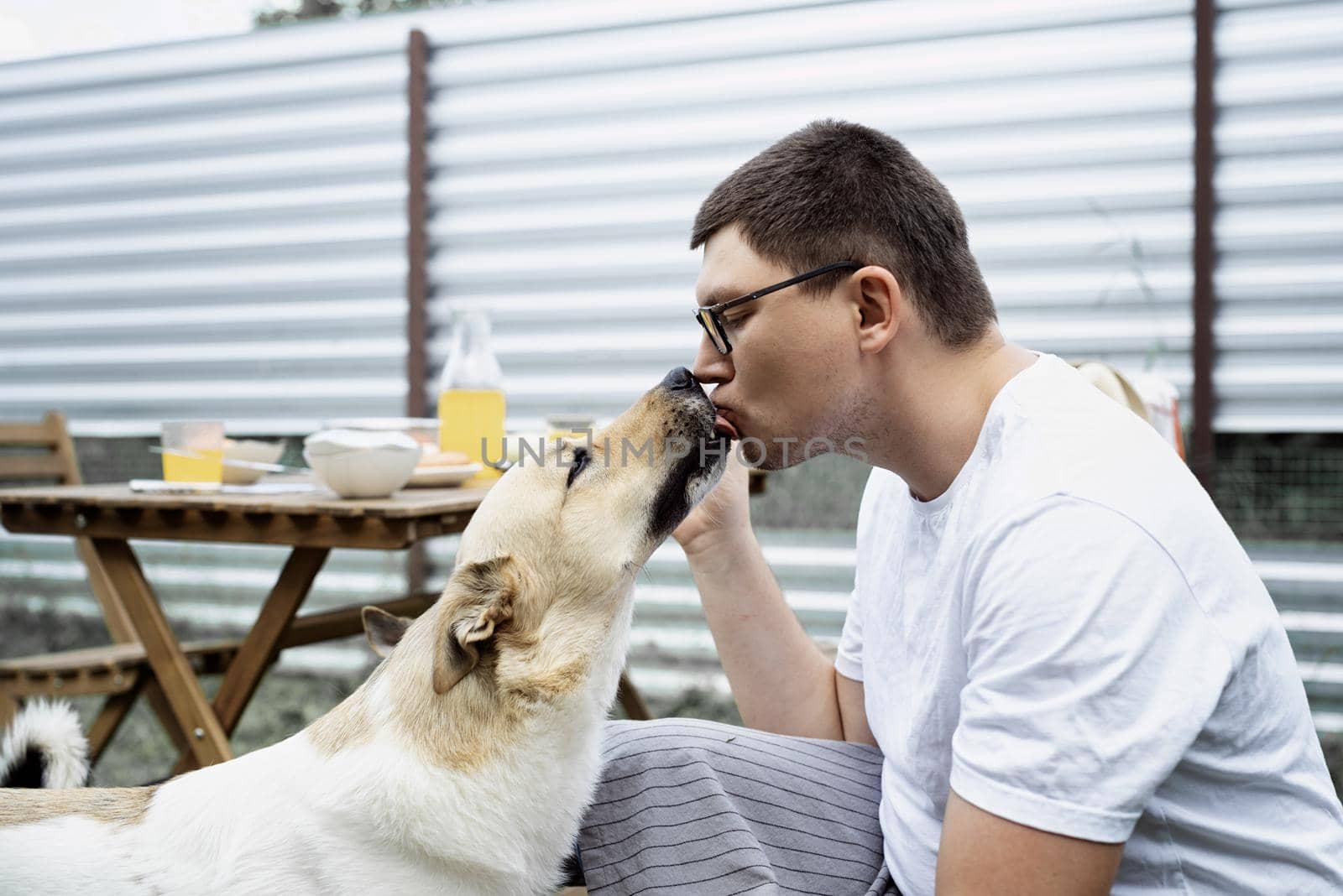Caucasian man kissing a dog, walking outdoors by Desperada