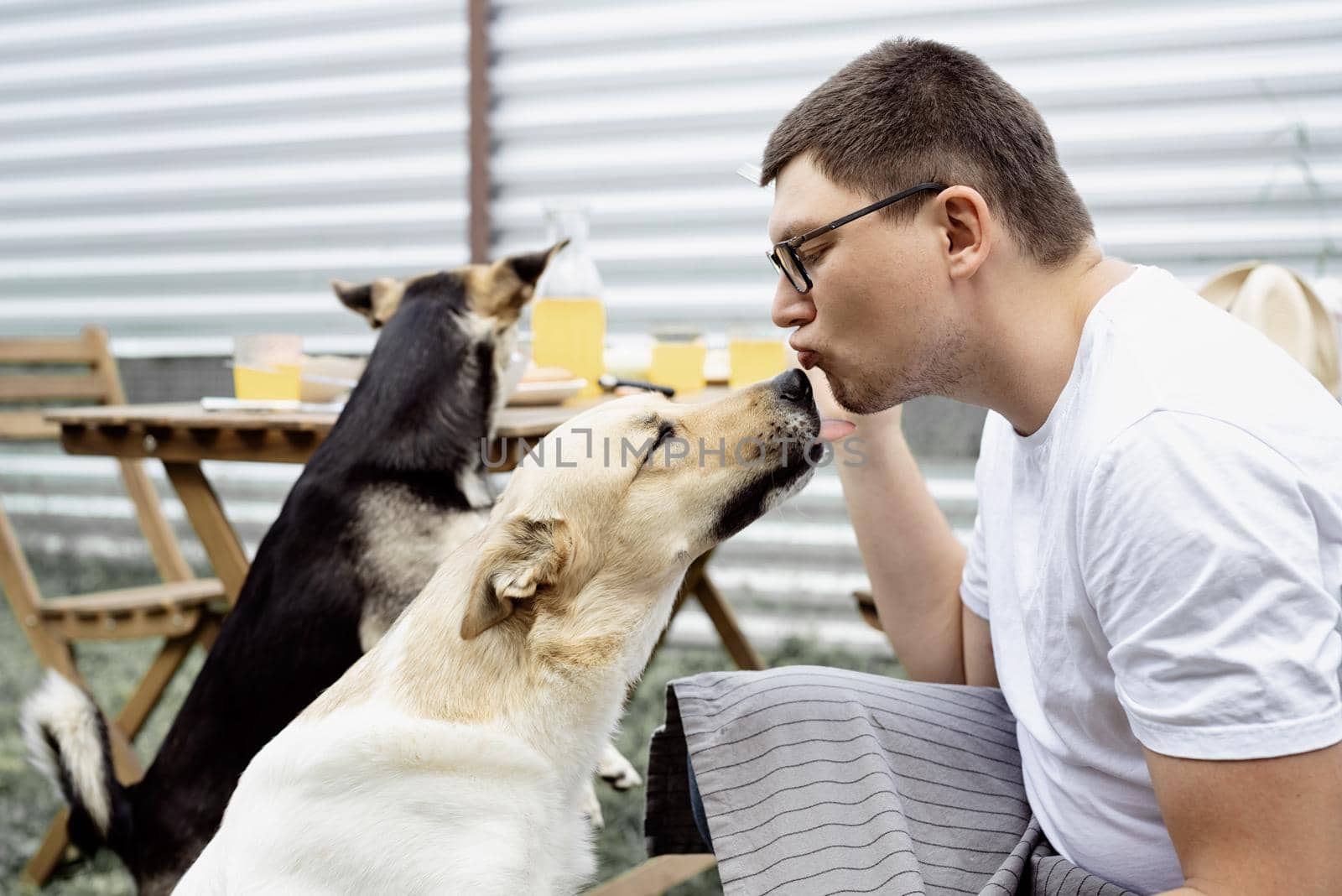 Caucasian man kissing a dog, walking outdoors in the backyard