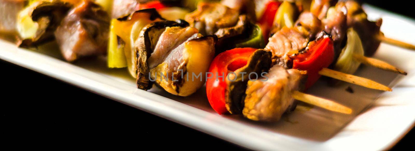 grilled skewers of meat and vegetables on a wooden board by Q77photo