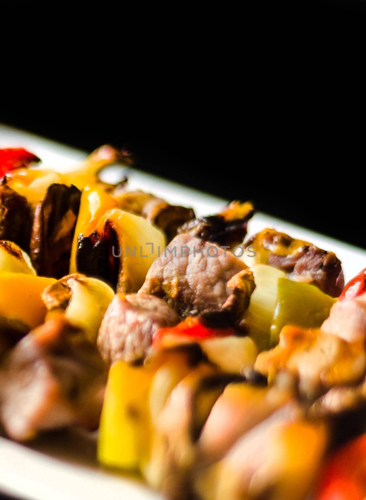 grilled skewers of meat and vegetables on a wooden board by Q77photo