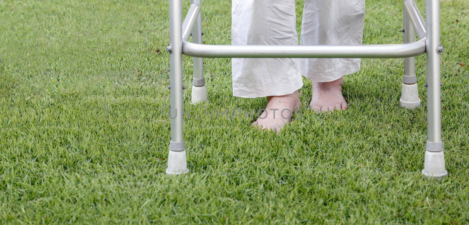 Elderly woman walking barefoot therapy on grass in backyard.