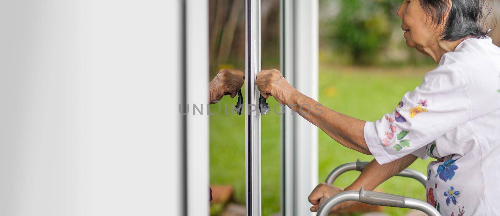 Elderly woman with key opening front door.