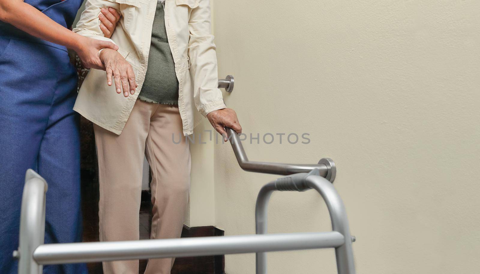 Elderly woman holding on handrail with caregiver