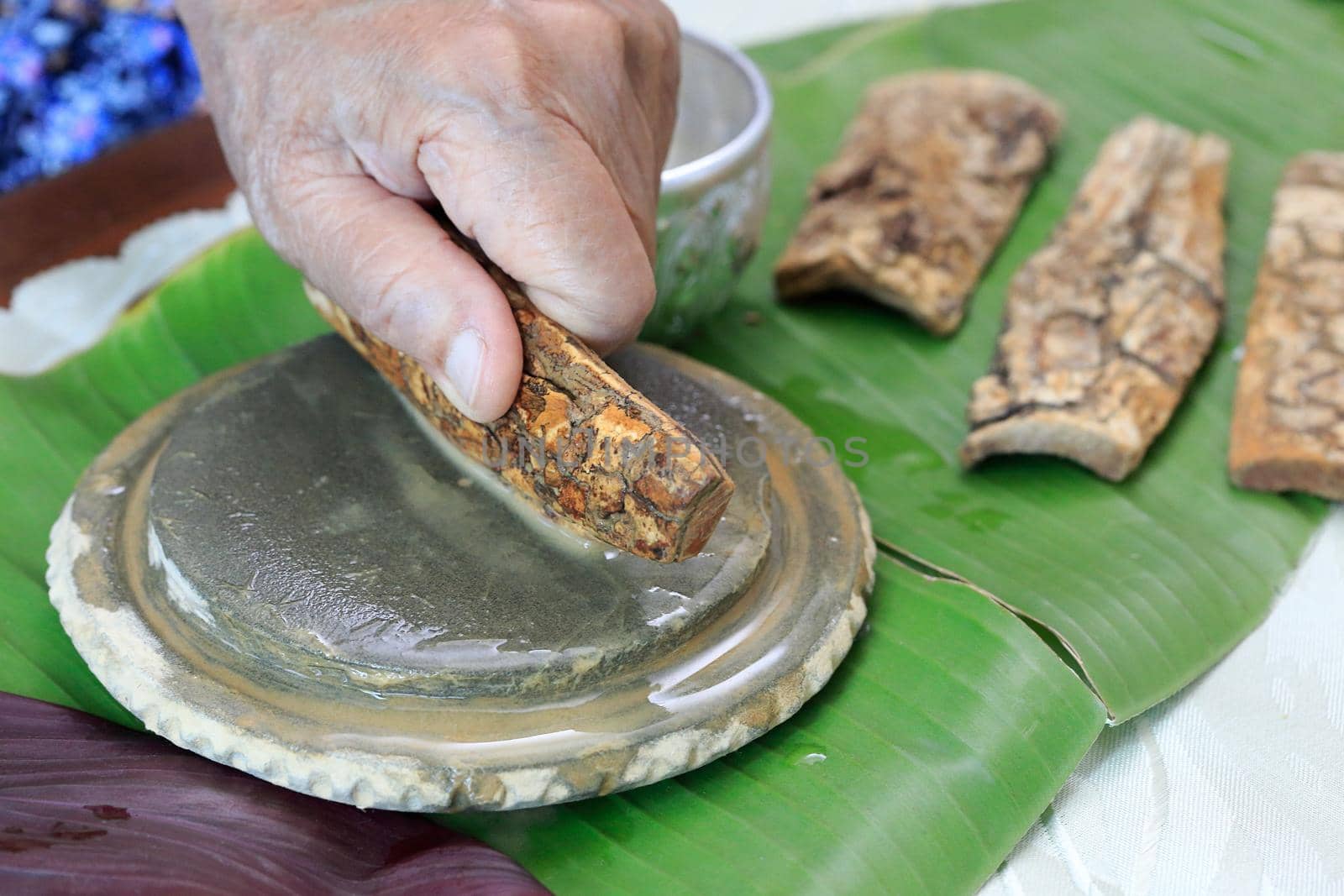 Thanaka herb bark scrubbing on kyauk pyin stone slab . thanaka is a popular cosmetic paste made from ground bark in Myanmar