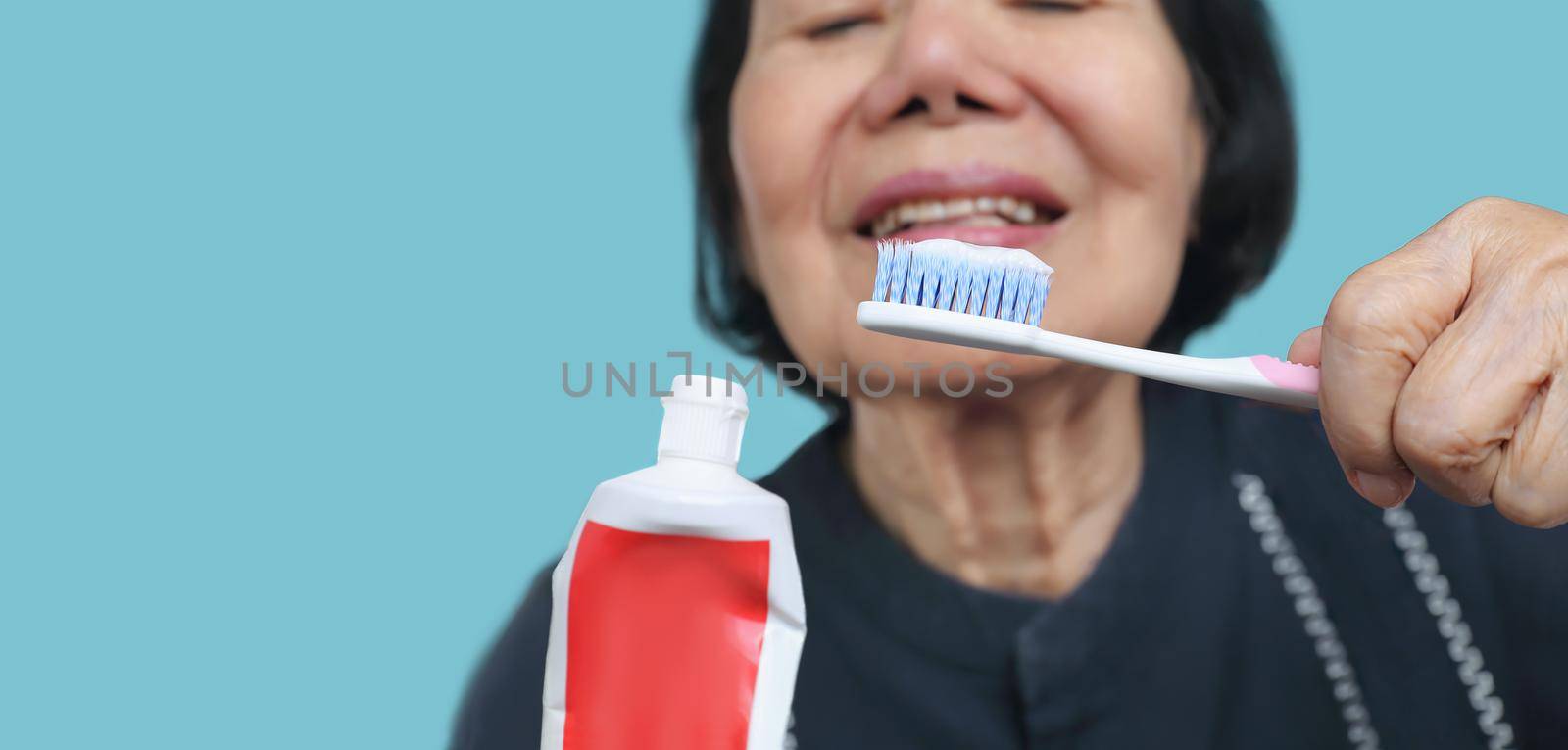 Asian elderly woman trying use toothbrush ,hand tremor . Dental health