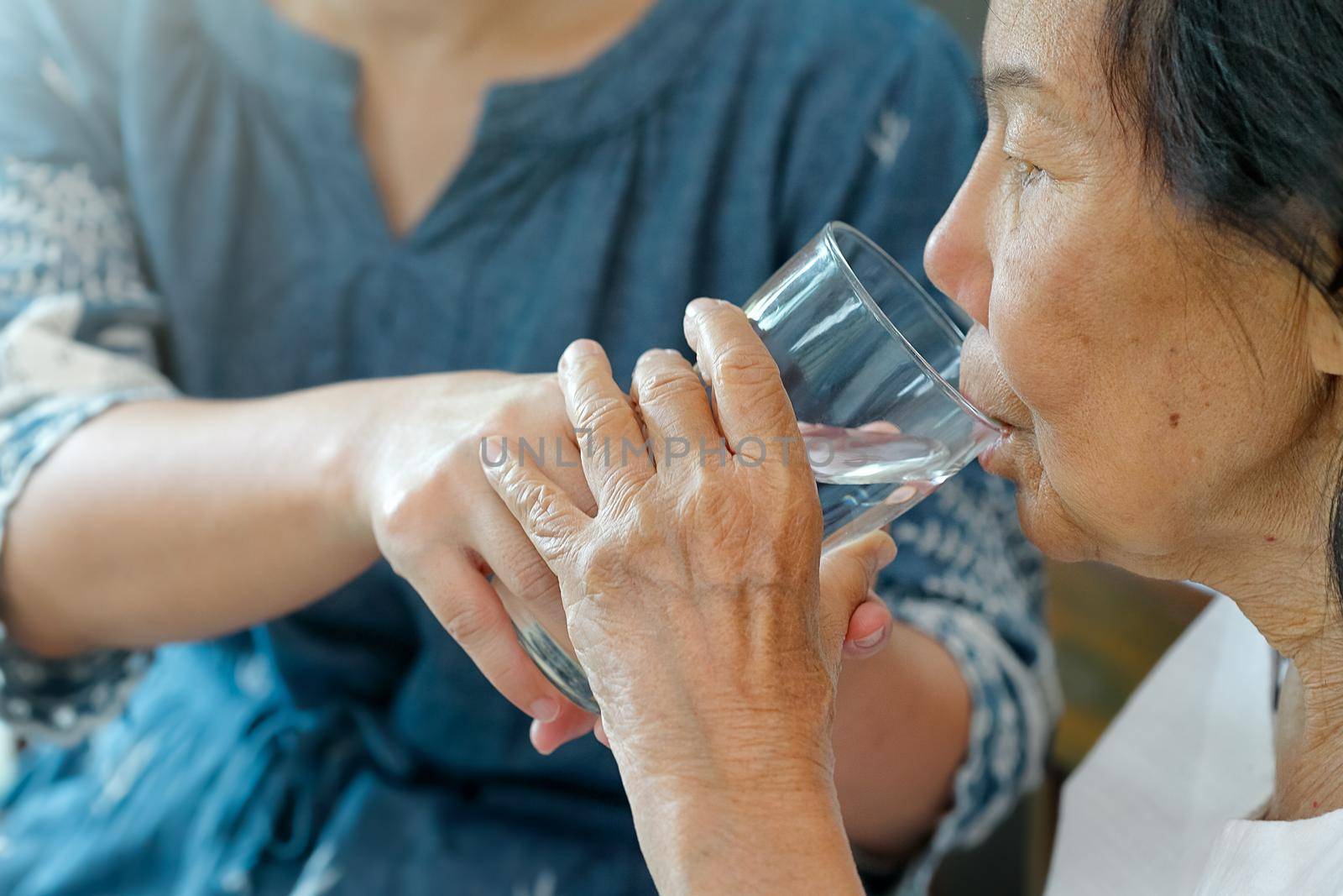 elderly woman gets a glass of water from caregiver