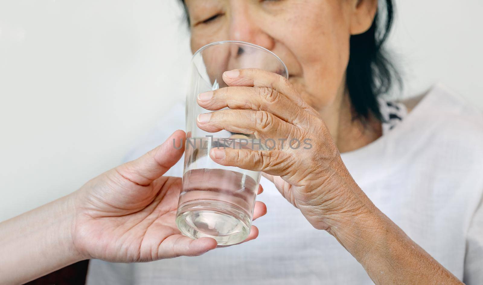 elderly woman gets a glass of water from caregiver