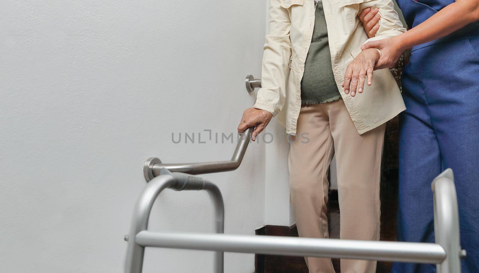 Elderly woman holding on handrail with caregiver by toa55