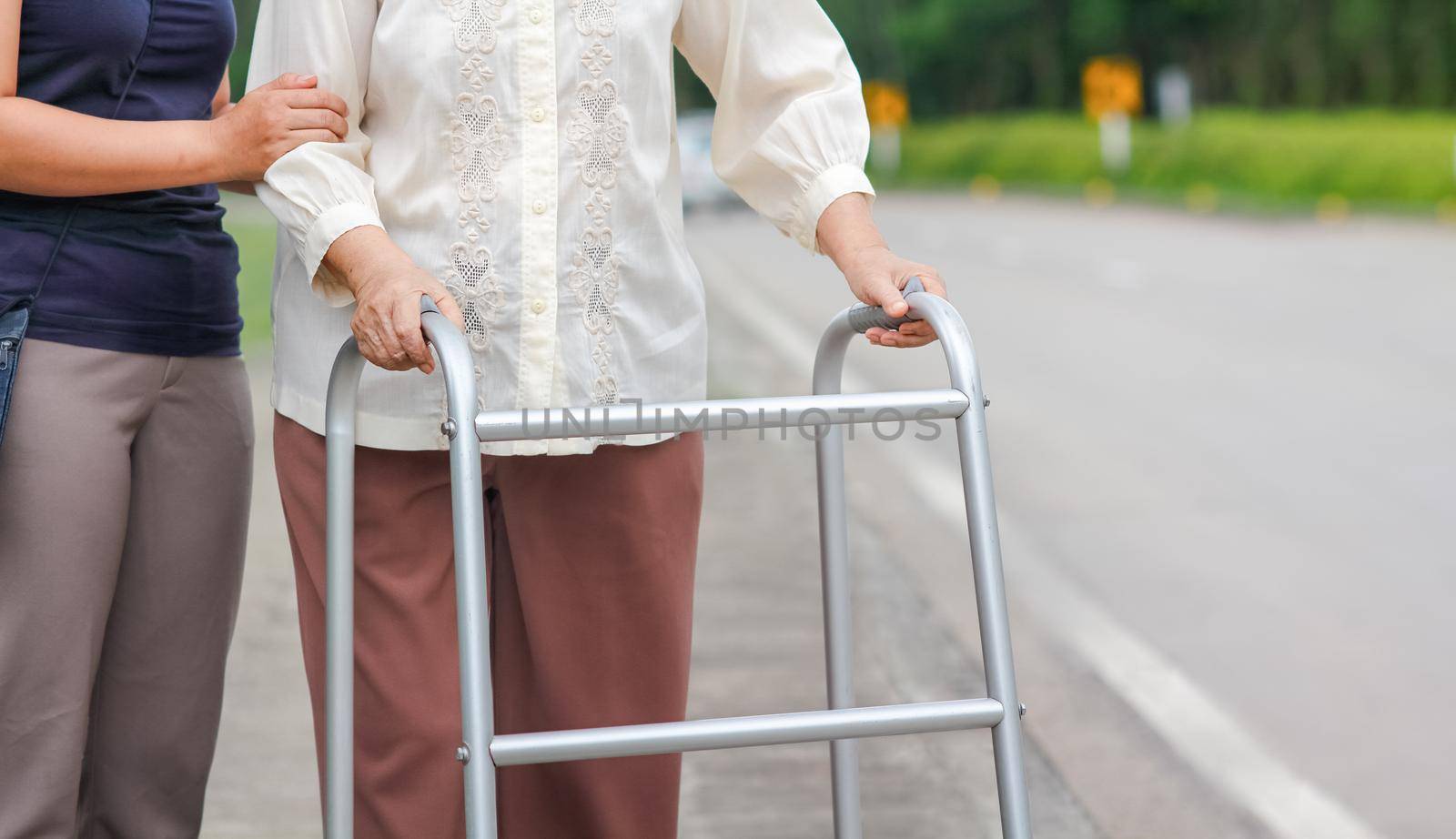senior woman using a walker cross street with caregiver