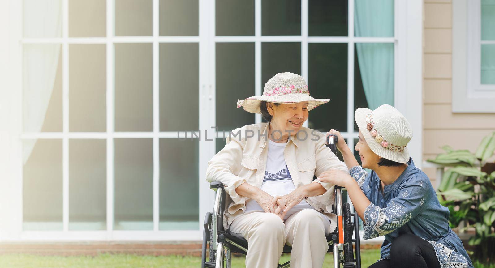 Elderly woman relax on wheelchair in backyard with daughter