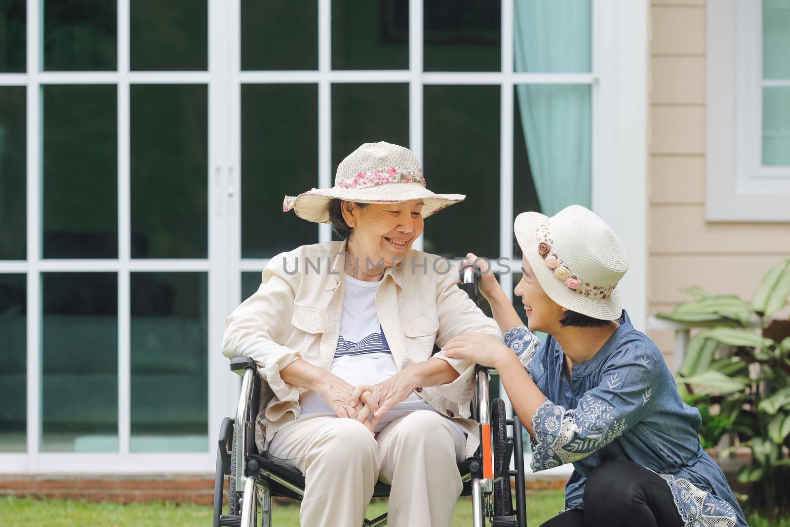 Elderly woman relax on wheelchair in backyard with daughter