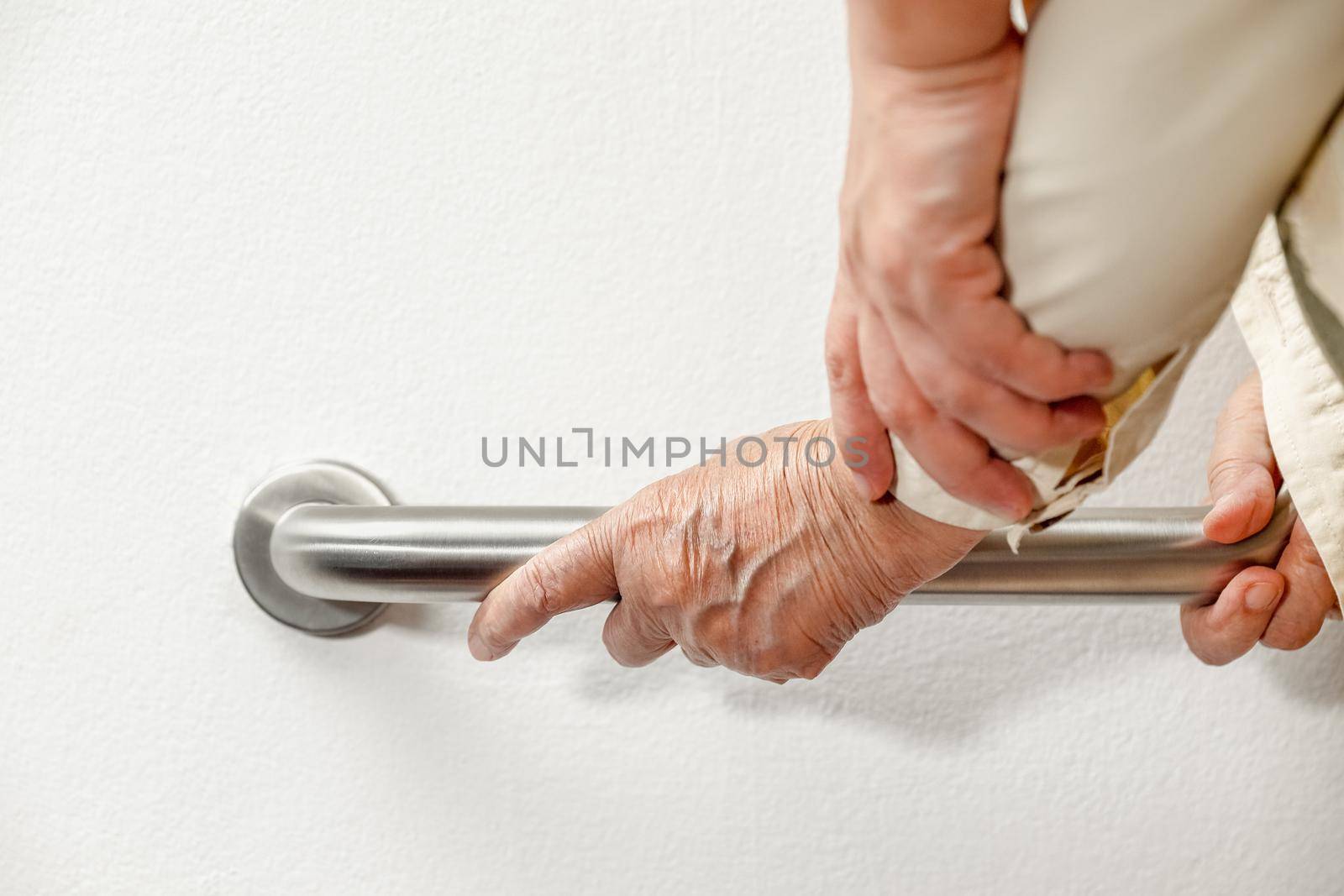 Elderly woman holding on handrail with caregiver